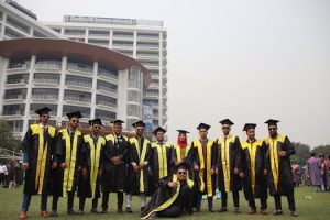 Graduating students celebrating with friends in front of university building.